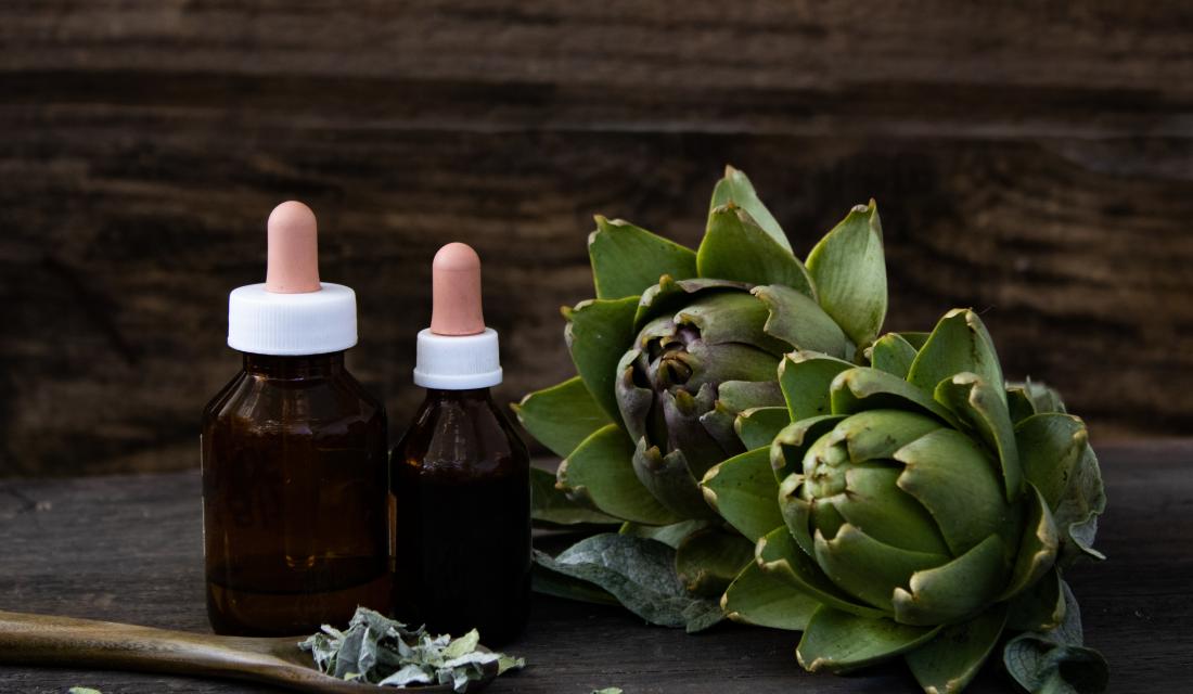 Artischocken, daneben zwei Fläschchen mit einer Tinktur