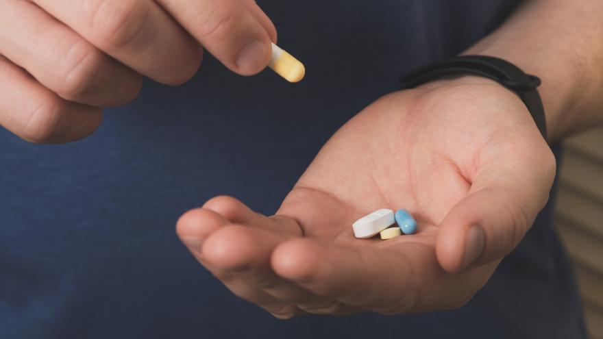 Eine Männerhand legt eine Tablette mit Nahrungsergänzungsmittel in die andere Hand, in der weitere Tabletten liegen