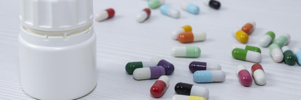 Tablettenkapseln liegen auf einem Tisch, daneben eine geschlossene Pillendose